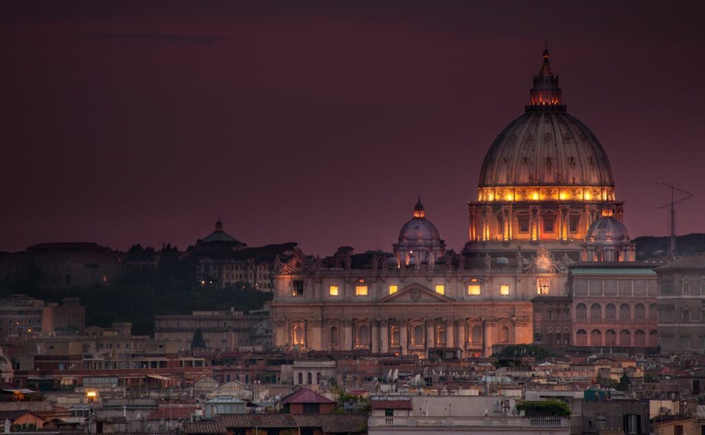 The dome of St. Peter's Basilica lit at dusk above the rooftops of Rome
