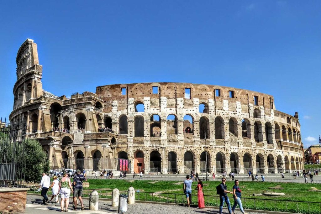 Turisti che passano davanti al Colosseo in una giornata di sole a Roma a settembre